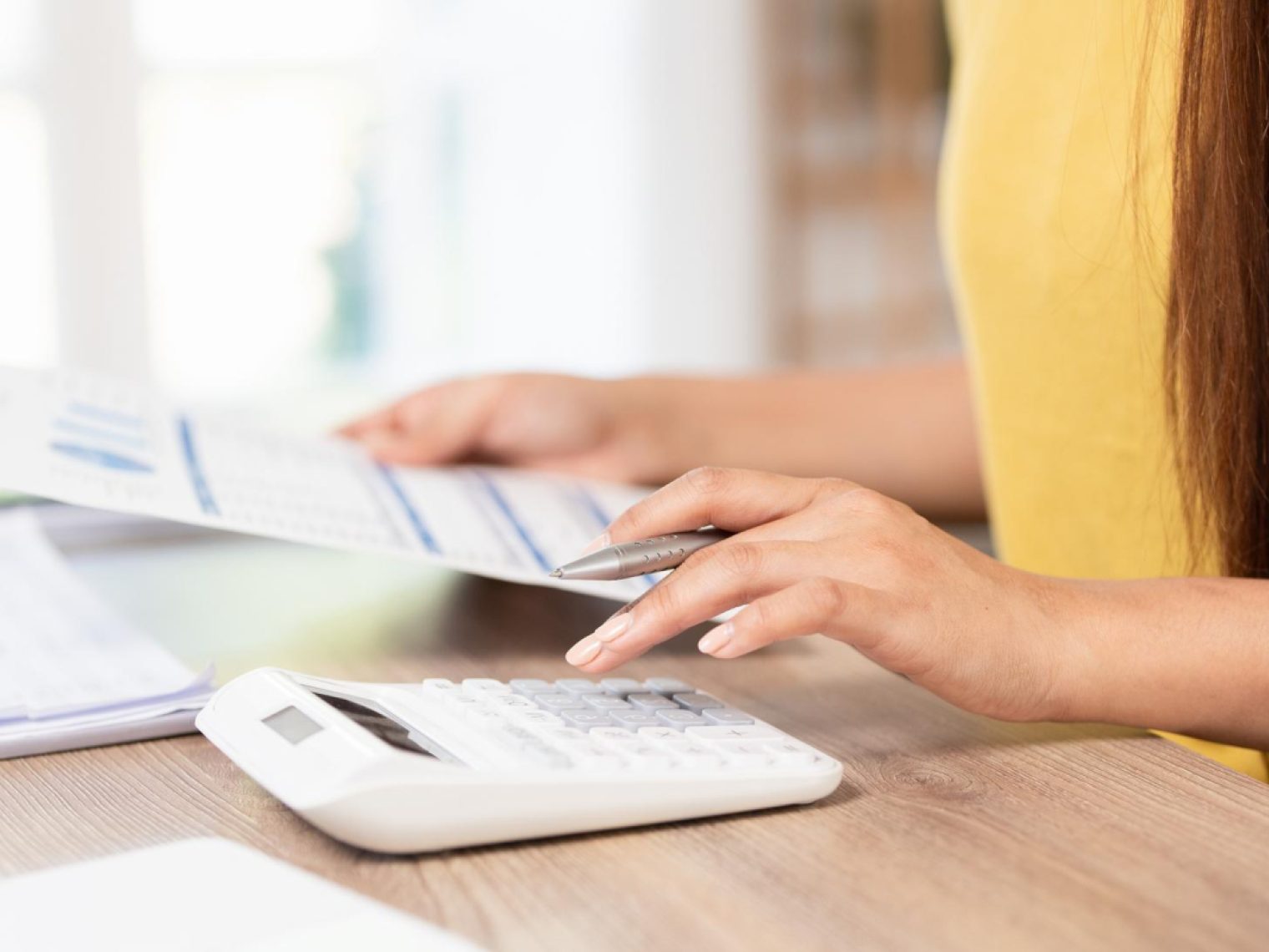 Woman using a calculator and reviewing financial documents.